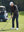 Model in dark grey softshell water resistant lightweight jacket preparing to tee off, full-body shot