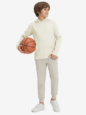 Full-body view of model holding basketball, wearing youth long sleeve hoodied with kangaroo pocket in cream.
