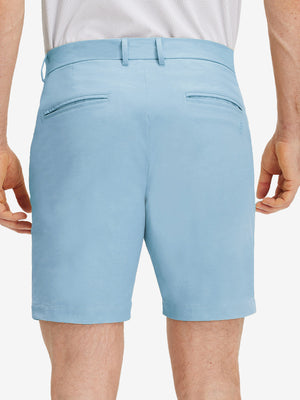 Back lower body shot of model wearing sky blue flat front flex cotton blend golf shorts