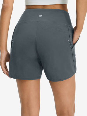 Back lower body shot of model wearing dark grey women's high waist 2 in 1 quick dry shorts with 7 pockets