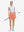 Front full body shot of model with golf gear wearing peach pink women's moisture-wicking athletic tennis skirts