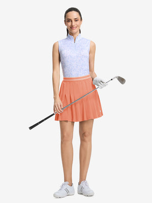 Front full body shot of model with golf gear wearing peach pink women's moisture-wicking athletic tennis skirts
