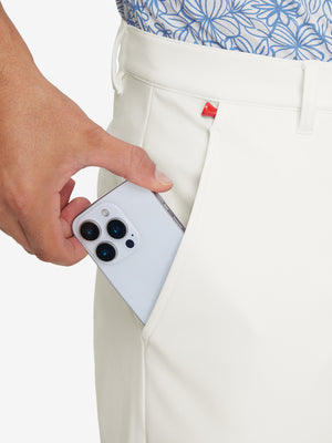 Side pocket detail of Golf Lightweight Fleece Lined Dress Pants in beige, holding smartphone