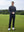 Model in dark grey long sleeve solid jersey polo holding a golf club outdoors, full-body shot