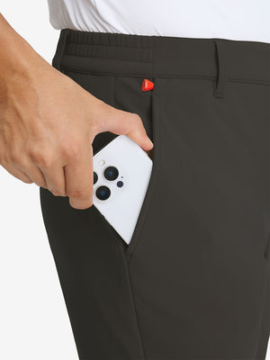Close-up detail showing phone being placed in the pocket of coffee water-resistant stretch heat-tech winter trousers