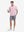 Full-body view of model holding takeaway drink cup in pink cotton blend plain shirt.