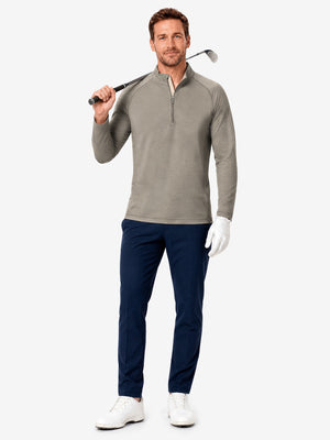 Full body model holding golf equipment for shooting, dry fit athletic 1/4 zip sweatshirt in taupe heather