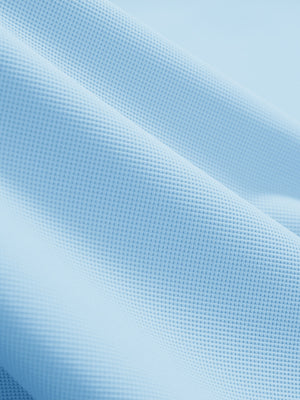 Close-up texture of light blue dry fit waffle textured collared golf shirts fabric showing weave detail.
