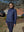 Model standing on a path with trees and houses, wearing navy women's lightweight fleece-lined puffer jacket.