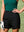 Model on outdoor golf course wearing black women's high waist 2 in 1 quick dry shorts with 7 pockets